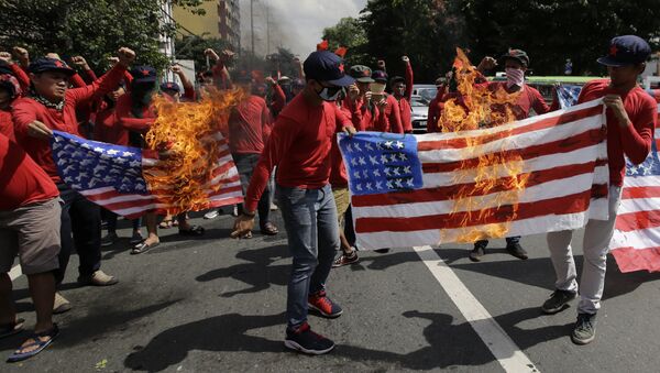 les manifestants brûlent un drapeau américain à Manille - Sputnik Afrique