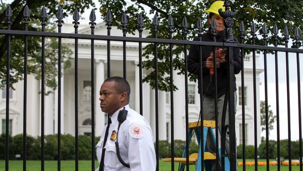 A Secret Service police officer walks outside the White House in Washington, Thursday, Oct. 23, 2014, as a maintenance worker performs fence repairs as part of a previous fence restoration project. - Sputnik Afrique