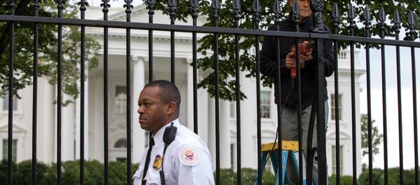 A Secret Service police officer walks outside the White House in Washington, Thursday, Oct. 23, 2014, as a maintenance worker performs fence repairs as part of a previous fence restoration project. - Sputnik Afrique
