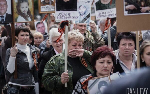 Anna Tuv, avec les portraits de son mari et sa fille, participe à une manifestation à Donetsk - Sputnik Afrique