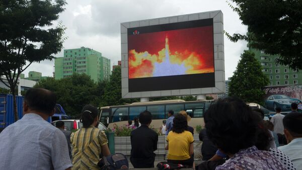 People watch as coverage of an ICBM missile test is displayed on a screen in a public square in Pyongyang on July 29, 2017. - Sputnik Afrique