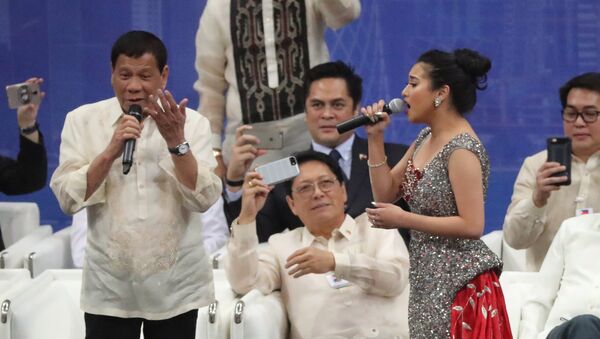 Rodrigo Duterte (L), President of the Philippines, sings a duet with a female singer during a gathering at Lusail Sports Arena in Lusail, 20km north of the Qatari capital on April 15, 2017. - Sputnik Afrique