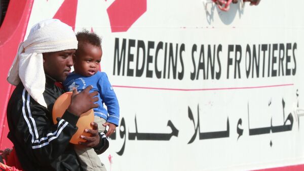 A migrant man carries a child as they disembark from the Italian rescue ship Vos Prudence run by NGO Medecins Sans Frontieres (MSF) as it arrives in the early morning of July 14, 2017 - Sputnik Afrique