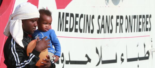 A migrant man carries a child as they disembark from the Italian rescue ship Vos Prudence run by NGO Medecins Sans Frontieres (MSF) as it arrives in the early morning of July 14, 2017 A migrant man carries a child as they disembark from the Italian rescue ship Vos Prudence run by NGO Medecins Sans Frontieres (MSF) as it arrives in the early morning of July 14, 2017 - Sputnik Afrique