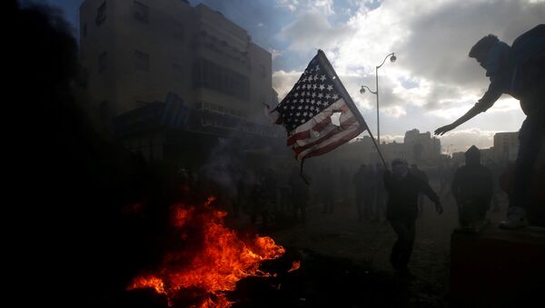 Палестинцы жгут американский флаг во время столкновений с израильской полицией в связи с протестами против решения Дональда Трампа признать Иерусалим столицей Израиля - Sputnik Afrique