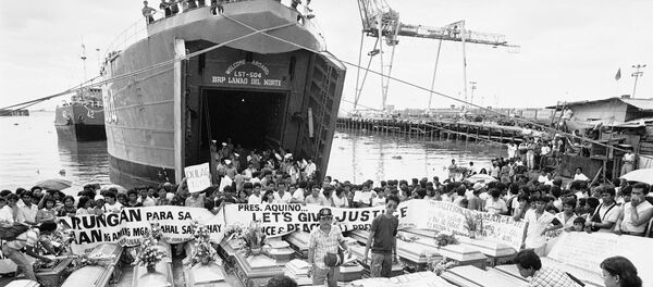 Relatives place a warning streamer on the coffins of victims in the century's worst sea tragedy prior to loading them aboard a Philippine Navy ship Jan. 3, 1988 in Manila, for their last trip home in Leyte province in central Philippines. - Sputnik Afrique
