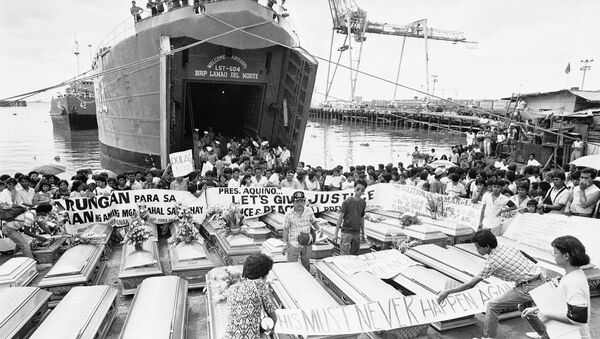 Relatives place a warning streamer on the coffins of victims in the century's worst sea tragedy prior to loading them aboard a Philippine Navy ship Jan. 3, 1988 in Manila, for their last trip home in Leyte province in central Philippines. - Sputnik Afrique