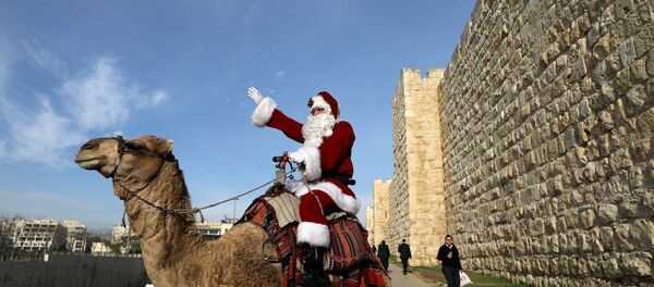 Israeli-Arab Issa Kassissieh rides a camel wearing a Santa Claus costume during the annual Christmas tree distribution by the Jerusalem municipality in Jerusalem's Old City - Sputnik Afrique