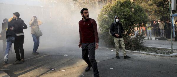 Iran, university students attend a protest inside Tehran University while a smoke grenade is thrown by anti-riot Iranian police, in Tehran, Iran, Saturday, Dec. 30, 2017 - Sputnik Afrique