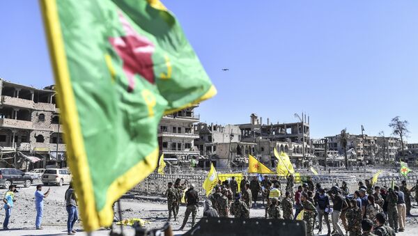 A fighter of the Syrian Kurdish People's Protection Units (YPG), a member group under the umbrella of the Syrian Democratic Forces (SDF), backed by US special forces, gather at the iconic Al-Naim square in Raqa on October 17, 2017. - Sputnik Afrique