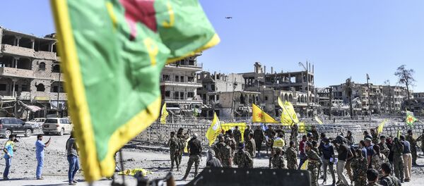 A fighter of the Syrian Kurdish People's Protection Units (YPG), a member group under the umbrella of the Syrian Democratic Forces (SDF), backed by US special forces, gather at the iconic Al-Naim square in Raqa on October 17, 2017. - Sputnik Afrique