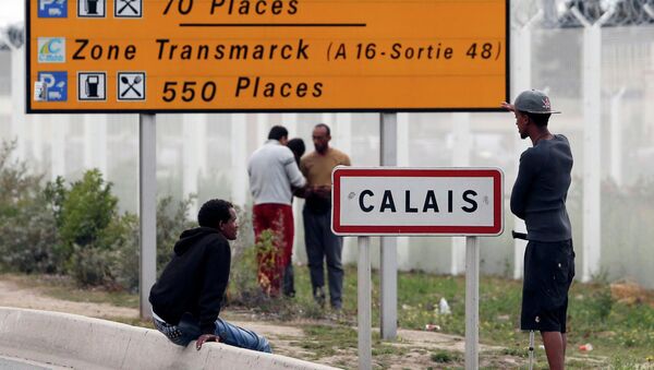 Migrants stand near a city sign along a road near the makeshift camp called The New Jungle in Calais, France, August 19, 2015 - Sputnik Afrique
