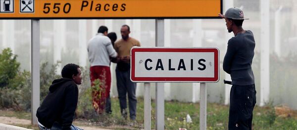 Migrants stand near a city sign along a road near the makeshift camp called The New Jungle in Calais, France, August 19, 2015 - Sputnik Afrique