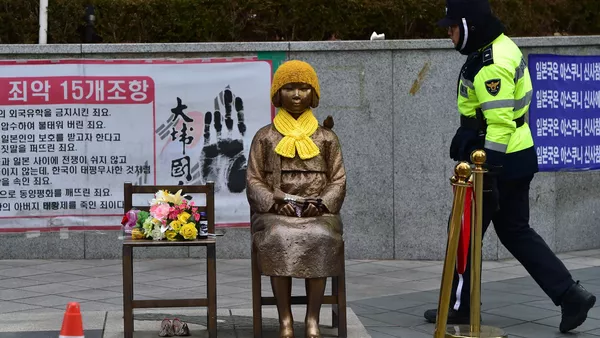 A South Korean policeman walks past a statue (C) of a teenage girl in traditional costume called the peace monument for former comfort women who served as sex slaves for Japanese soldiers during World War II, in front of the Japanese embassy in Seoul on December 29, 2015. - Sputnik Afrique