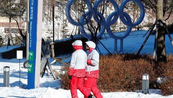 Volunteers walk beside the Olympic rings at the Alpensia resort for the upcoming 2018 Pyeongchang Winter Olympic Games in Pyeongchang, South Korea, January 23, 2018 - Sputnik Afrique