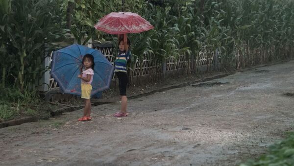 Дети укрываются от дождя под зонтами на юге Пхеньяна - Sputnik Afrique