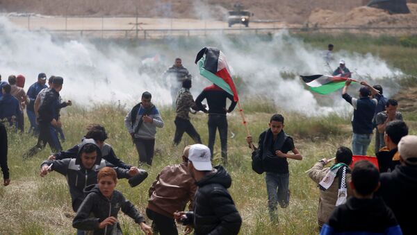 Palestinians run from tear gas fired by Israeli troops during clashes, during a tent city protest along the Israel border with Gaza, demanding the right to return to their homeland, east of Gaza - Sputnik Afrique
