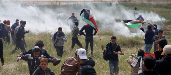 Palestinians run from tear gas fired by Israeli troops during clashes, during a tent city protest along the Israel border with Gaza, demanding the right to return to their homeland, east of Gaza - Sputnik Afrique