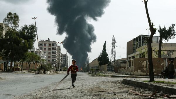 A child runs along a street in front of clouds of smoke billowing following a reported air strike on Douma, the main town of Syria's rebel enclave of Eastern Ghouta - Sputnik Afrique