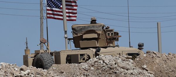 A U.S. soldier sits on an armored vehicle behind a sand barrier at a newly installed position near the tense front line between the U.S-backed Syrian Manbij Military Council and the Turkish-backed fighters, in Manbij, north Syria, Wednesday, April 4, 2018 - Sputnik Afrique