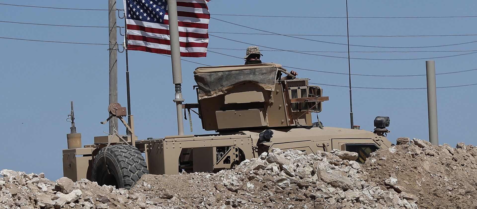 Un soldat américain est assis sur un véhicule blindé derrière une barrière de sable à une position nouvellement installée près de la ligne de front tendue entre le Conseil militaire syrien de Manbij soutenu par les États-Unis et les combattants soutenus par la Turquie, à Manbij, dans le nord de la Syrie, le mercredi 4 avril 2018 - Sputnik Afrique, 1920, 11.02.2021