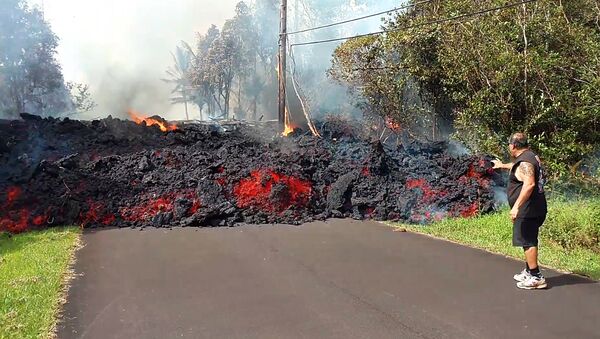 In this photo taken from video an unidentified man gets close to a lava flow advancing down a road in the Leilani Estates subdivision near Pahoa on the island of Hawaii Monday, May 7, 2018 - Sputnik Afrique