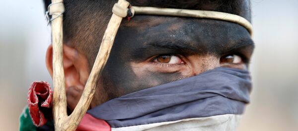 A Palestinian demonstrator with a slingshot looks on during a protest against U.S. embassy move to Jerusalem and ahead of the 70th anniversary of Nakba, at the Israel-Gaza border, east of Gaza City May 14, 2018. - Sputnik Afrique