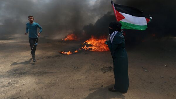 A woman holds a Palestinian flag as a demonstrator runs during a protest against U.S. embassy move to Jerusalem and ahead of the 70th anniversary of Nakba, at the Israel-Gaza border in the southern Gaza Strip May 14, 2018. - Sputnik Afrique