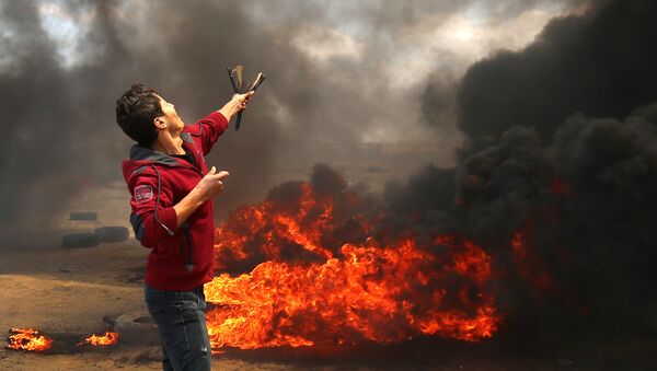 A Palestinian man uses a slingshot during clashes with Israeli forces along the border with the Gaza strip east of Khan Yunis on May 14, 2018, as Palestinians protest over the inauguration of the US embassy following its controversial move to Jerusalem - Sputnik Afrique