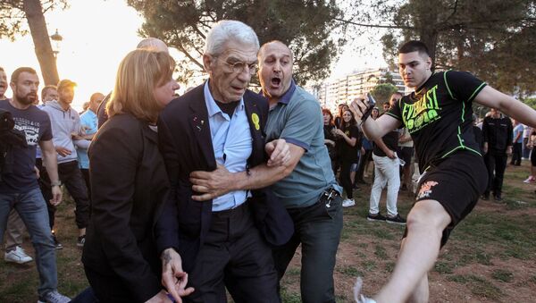 The mayor of Greece’s second city, Thessaloniki, Yiannis Boutaris (C) is helped as he is assulted by suspected far-right members at a rally in Thessaloniki on May 19, 2018. - Sputnik Afrique