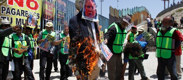 Demonstrators burn an effigy depicting U.S. President Donald Trump during a protest against the immigration policies of Trump's government near the border fence between Mexico and the U.S., in Tijuana, Mexico May 10, 2018 - Sputnik Afrique