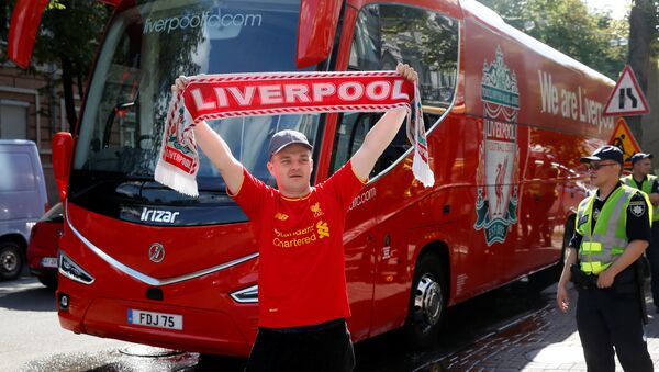 Soccer Football - Champions League - Fans In Kiev Ahead Of The Champions League Final - Kiev, Ukraine - May 25, 2018 Liverpool fan poses with a scarf in front of the team bus - Sputnik Afrique