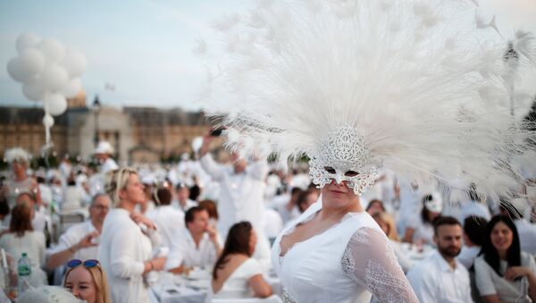 A guest poses near Les Invalides during the Diner en Blanc (Dinner in White) in Paris, France, June 3, 2018. Diners dressed head to toe in white and bringing with them white tablecloths, glassware and other finery, gather for an impromptu open-air dinner, which takes place at a different place in Paris every year. REUTERS/Benoit Tessier - Sputnik Afrique