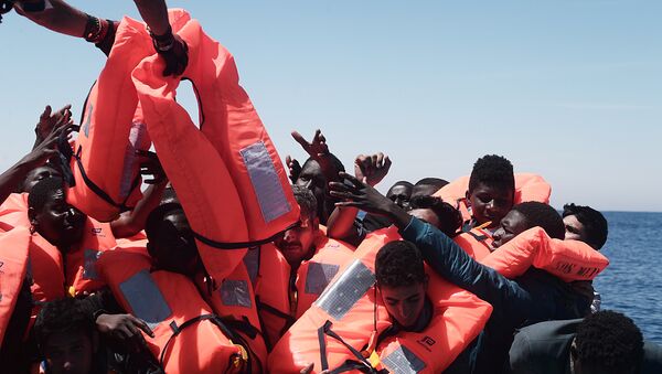 Migrants in an overcrowded plastic raft reach out for life jackets during a search and rescue operation by rescue ship Aquarius, operated by SOS Mediterranean and Doctors without Borders, in central Mediterranean Sea May 18, 2017 - Sputnik Afrique