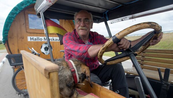 Soccer fan from Pforzheim, Germany, Hubert Wirth, 70, with his dog Hexe, drives his tractor with a trailer to attend the FIFA 2018 World Cup in Russia near the village of Yasen, Belarus June 7, 2018 - Sputnik Afrique