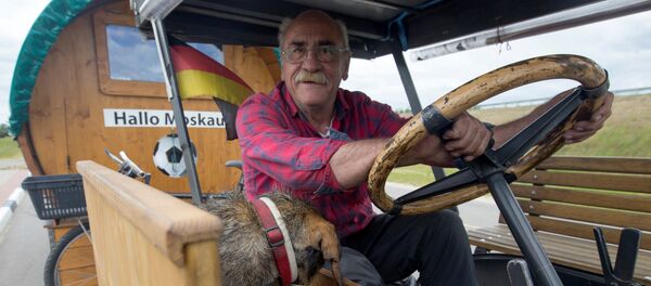 Soccer fan from Pforzheim, Germany, Hubert Wirth, 70, with his dog Hexe, drives his tractor with a trailer to attend the FIFA 2018 World Cup in Russia near the village of Yasen, Belarus June 7, 2018 - Sputnik Afrique