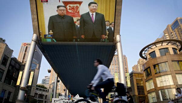 People bicycle past a giant TV screen broadcasting the meeting of North Korean leader Kim Jong Un and Chinese President Xi Jinping during a welcome ceremony at the Great Hall of the People in Beijing, Tuesday, June 19, 2018 - Sputnik Afrique