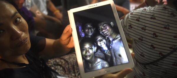 Verwandte einer von den Jungen zeigt das Bild mit den in der Höhle eingeschlossenen Kindern - Sputnik Afrique