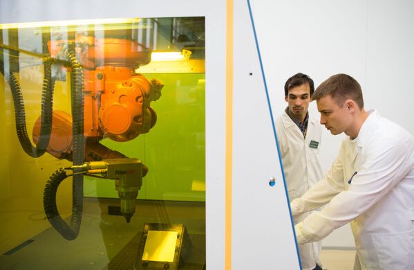 Des aspirants de l'Institut des technologies laser et plasma effectuent les réglages d'une machine avec un manipulateur robotisé et un laser à fibre ytterbium d'une puissance de 400 W. - Sputnik Afrique