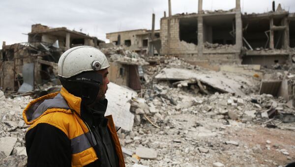 Forty-five-year-old Samir Salim (L) who along with his three brothers are members of the White Helmets rescue forces looks out at destroyed buildings in the town of Medeira in Syria's rebel-held Eastern Ghouta area on February 12 2018. - Sputnik Afrique