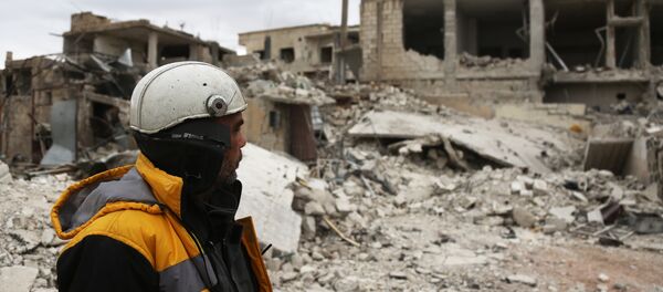 Forty-five-year-old Samir Salim (L) who along with his three brothers are members of the White Helmets rescue forces looks out at destroyed buildings in the town of Medeira in Syria's rebel-held Eastern Ghouta area on February 12 2018. - Sputnik Afrique