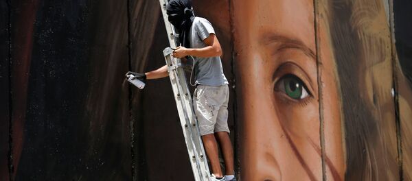 A foreign artist paints on the Israeli wall a mural depicting Palestinian teen Ahed Tamimi who is detained by Israel, in Bethlehem, in the occupied West Bank, July 25, 2018. - Sputnik Afrique