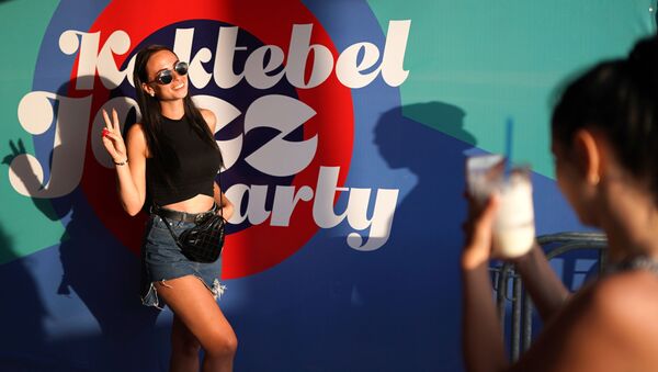 Девушка фотографируется у баннера музыкального фестиваля Koktebel Jazz Party 2018 - Sputnik Afrique