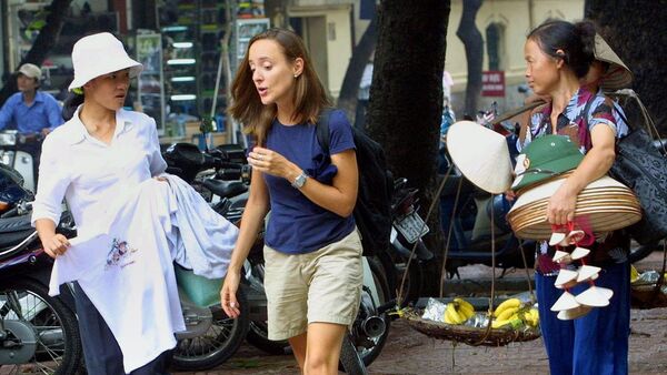 A foreign tourist (C) tries to elude T-shirt and souvenir vendors as she walks down a Hanoi street, 31 July 2002. - Sputnik Afrique