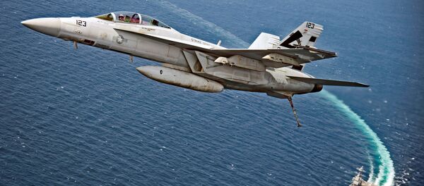 An F/A-18F Super Hornet jet flies over the USS Gerald R. Ford as the U.S. Navy aircraft carrier tests its EMALS magnetic launching system, which replaces the steam catapult, and new AAG arrested landing system in the Atlantic Ocean - Sputnik Afrique