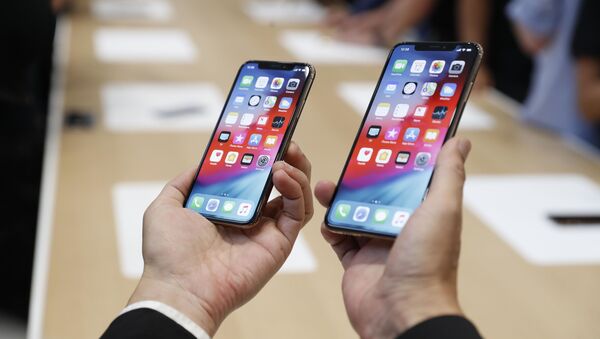 Мужчина держит в руках новые телефоны Apple iPhone XS и XS Max на презентации новых продуктов Apple в американском городе Купертино - Sputnik Afrique