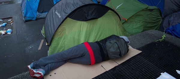 A person sleep next to tents during the evacuation of a makeshift camp on June 16, 2016 in Paris. - Sputnik Afrique