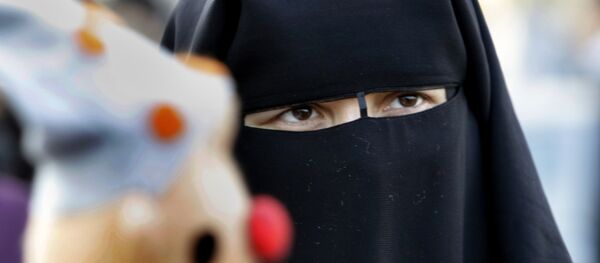 An Egyptian woman wearing Isalmic niqab, which covers everything but the eyes, buys a puppet as she celebrates Islamic Eid al-Adha, or Feast of the Sacrifice, in Cairo, Egypt, Sunday, Nov. 6, 2011. - Sputnik Afrique