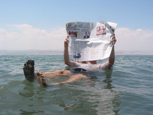 Un homme lit un journal en mer Morte Un homme lit un journal en mer Morte - Sputnik Afrique