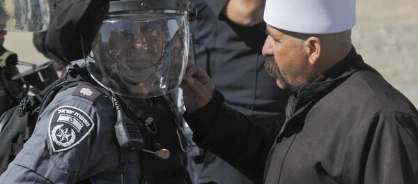 Un membre du communauté druze parle à un membre des forces de sécurité israéliennes lors d'une manifestation contre les élections municipales dans le village de Majdal Chams - Sputnik Afrique